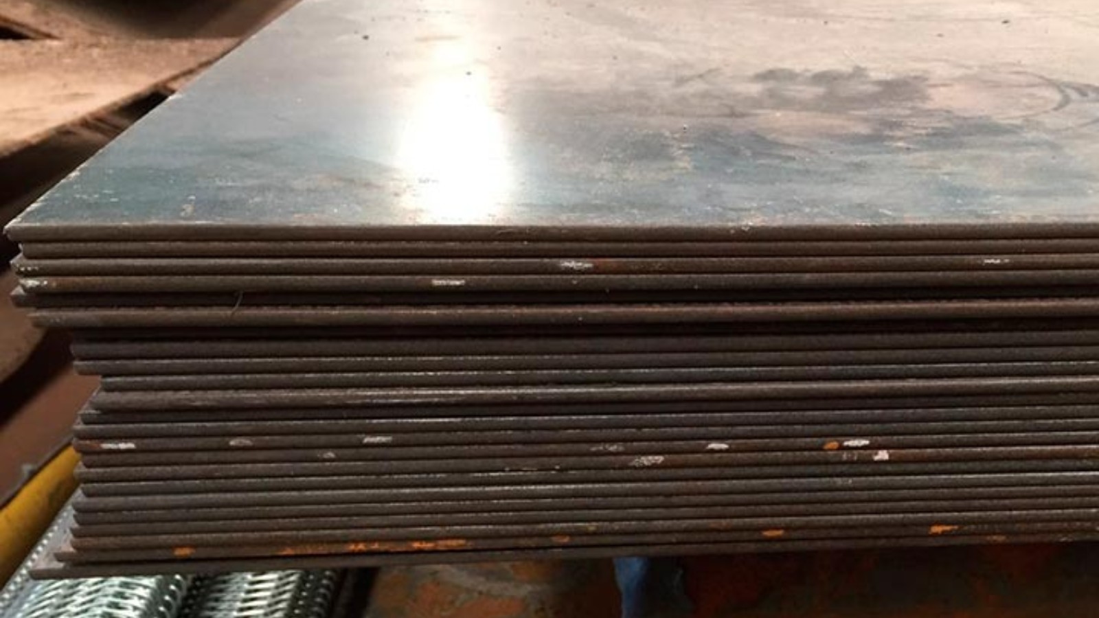 Chapas de acero F36 laminadas en caliente apiladas en playa de acopio industrial.