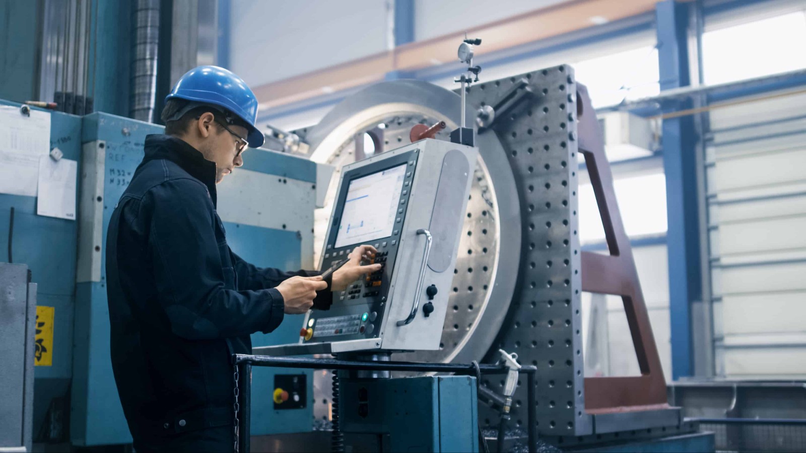 Operario frente a panel CNC en planta metalúrgica argentina — automatización industrial metalmecánica