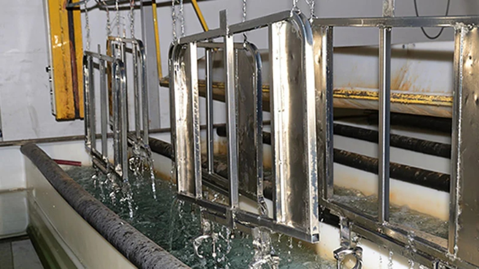 Piezas de acero en baño de galvanoplastia con electrodeposición de zinc, proceso industrial anticorrosivo